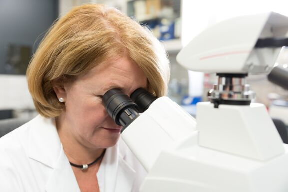 Woman scientist in a lab looking into a microscope