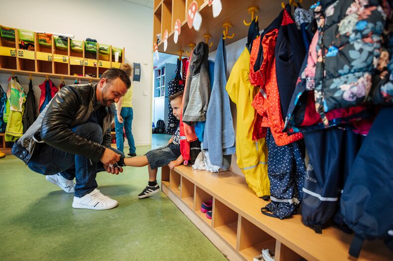 Father putting on his child's shoes at the kindergarden