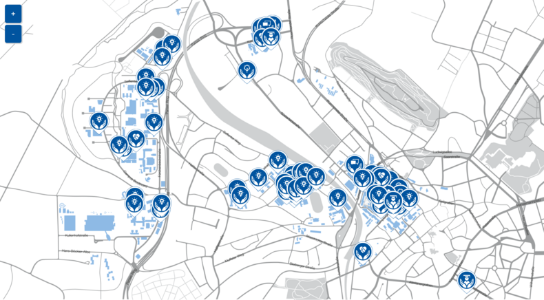 Shown is the stylized campus plan of the RWTH with the large areas Mitte, Hörn and Mela-ten. Spo-radic markers have been placed. These are in the form of location pins and each have different icons.  All icons are made up of two open hands at the bottom and a symbol. There are five different icons:  A light bulb - it stands for the "research" field of action. A person with a doctoral hat - it stands for the field of action "study and teaching". A flower, where the blossom represents a cogwheel, stands for the field of action "Operation".  A symbol of two intersecting speech bubbles stands for area "Governance".  The symbol of two shaking hands forming a heart shape symbolizes the field of action "International - Social - Society".   Each pin stands for a project, a contact person, an initiative or similar, which deals with a specific sustainability topic. The pins are located at deposited addresses.