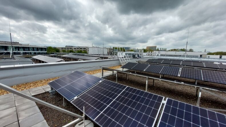 The picture shows several rows of solar panels on a roof. A cloudy sky is shown in the background.